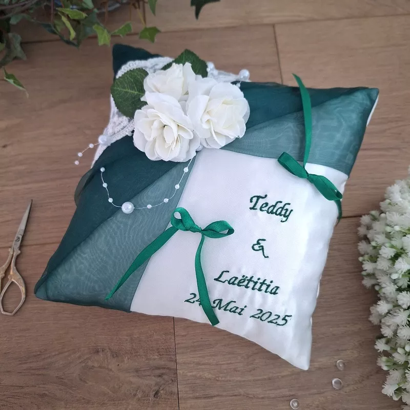 Coussin satin blanc avec organza vert émeraude et décor roses blanche, brodé aux prénoms et date de l'événement